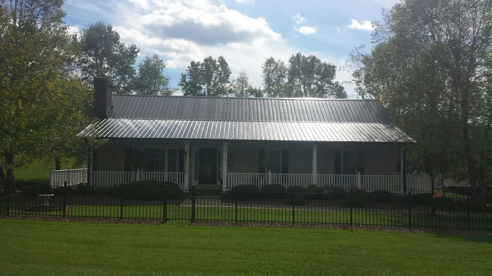 Gray metal roof on a brick ranch with a full width front porch — Gutter Guard Installation work by our crew in Pine Prairie