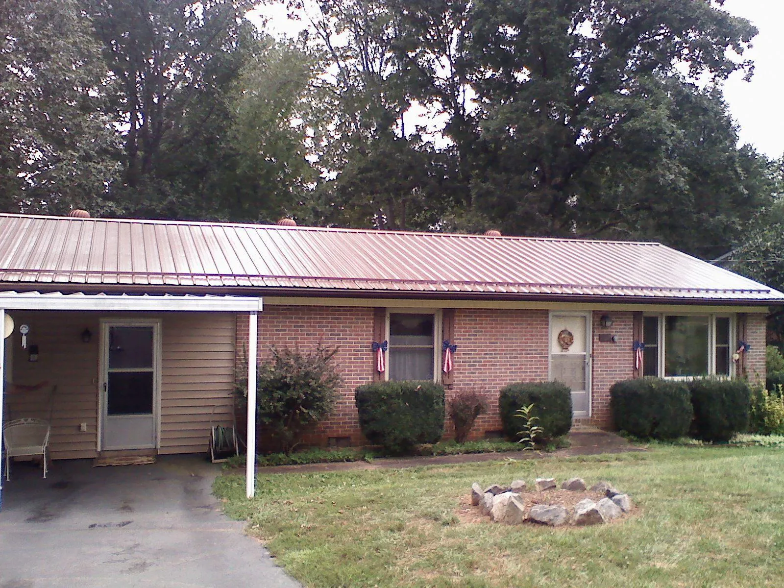 Bronze metal roof and carport on a brick ranch home — Roof Repair work by our crew in Pine Prairie