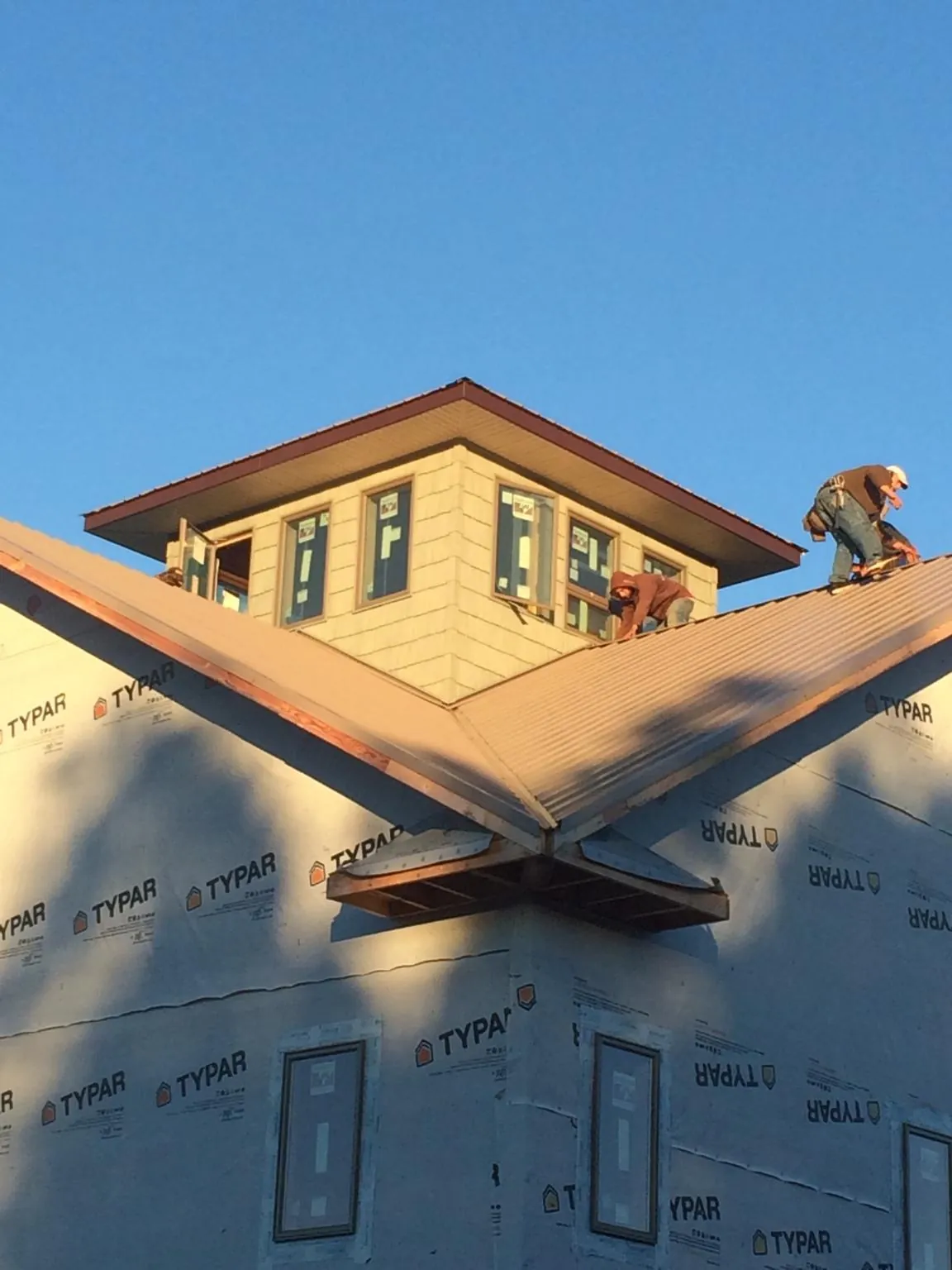 Roofers working around a rooftop cupola on a new metal roof at sunset — Roof Waterproofing in Pine Prairie by Roofing Brothers